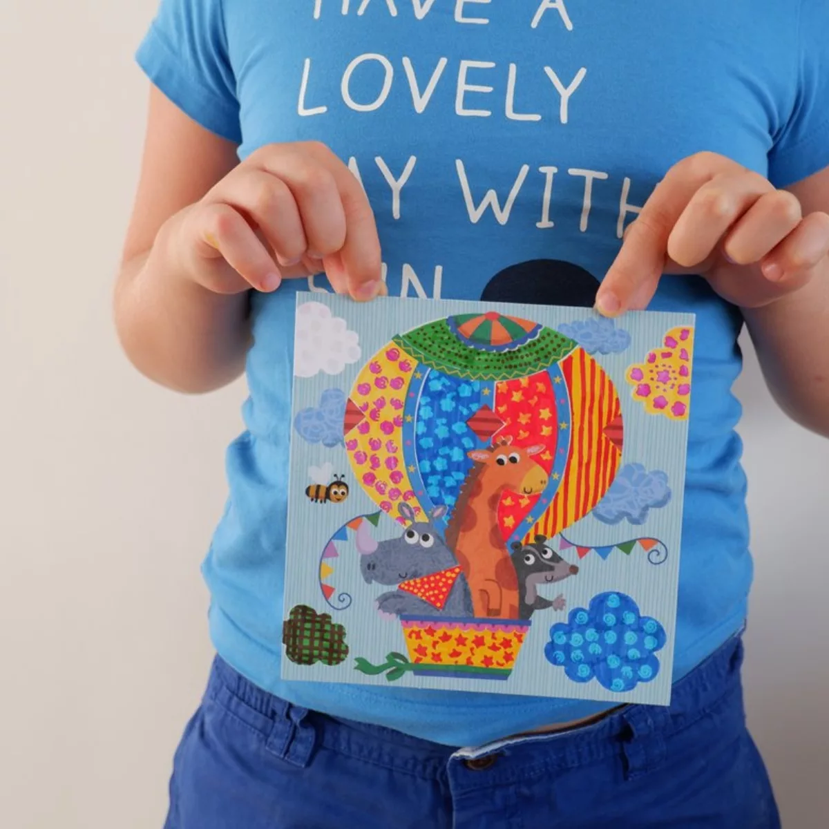 Дете държи оцветена картина от творчески комплект с магически флумастери