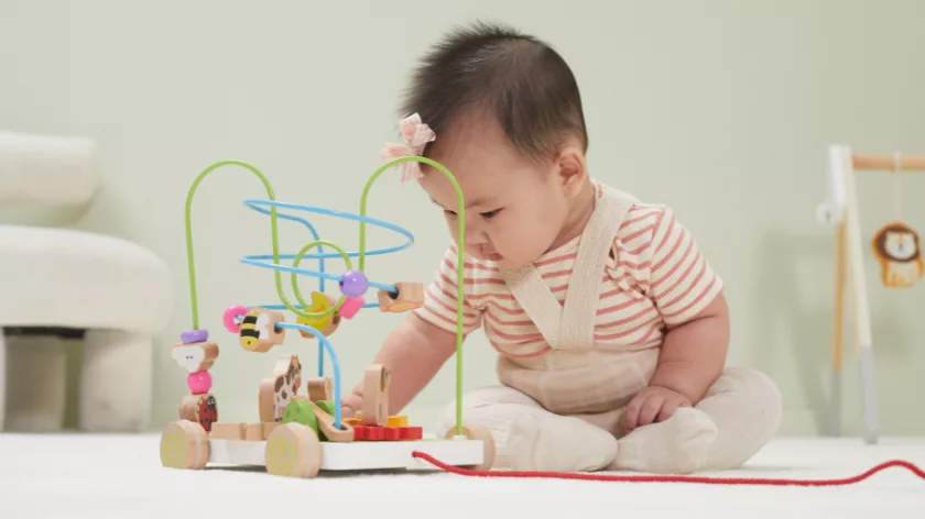 Бебе играе с дървена лабиринт игра с мъниста за развитие на моториката