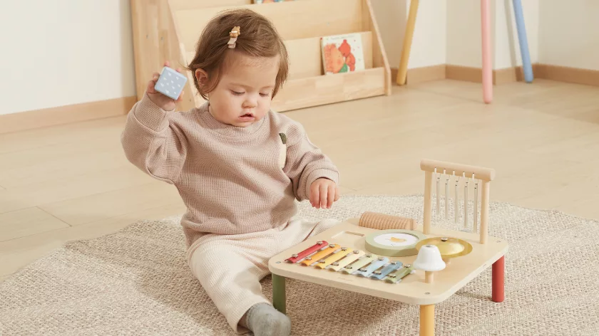 Дете играе с дървен музикален комплект и ксилофон – образователна играчка