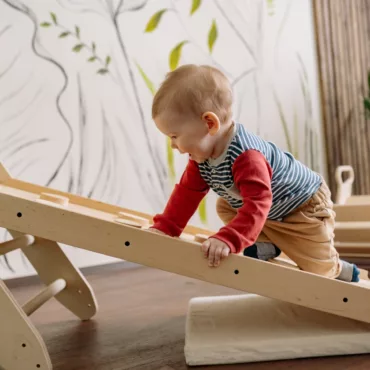 Бебе играе с дървена катерушка и Монтесори играчки за развитие на моториката