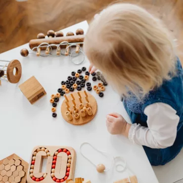 Дете играе с дървени Монтесори образователни играчки и сортери на маса