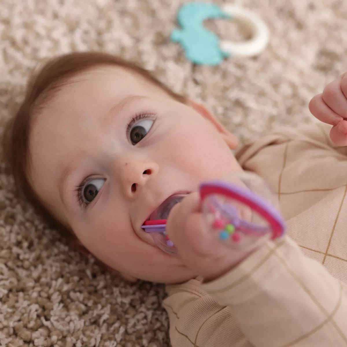 Бебе играе с дрънкалка с цветни мъниста – безопасна бебешка играчка