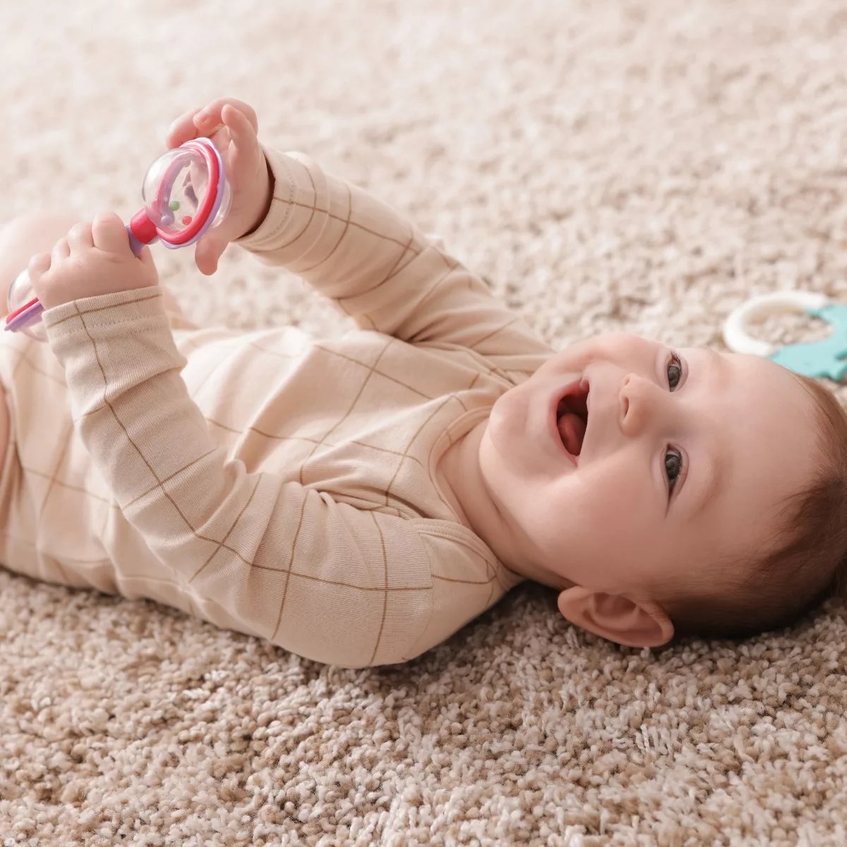 Бебе играе с прозрачна дрънкалка с мъниста – безопасна играчка за количка