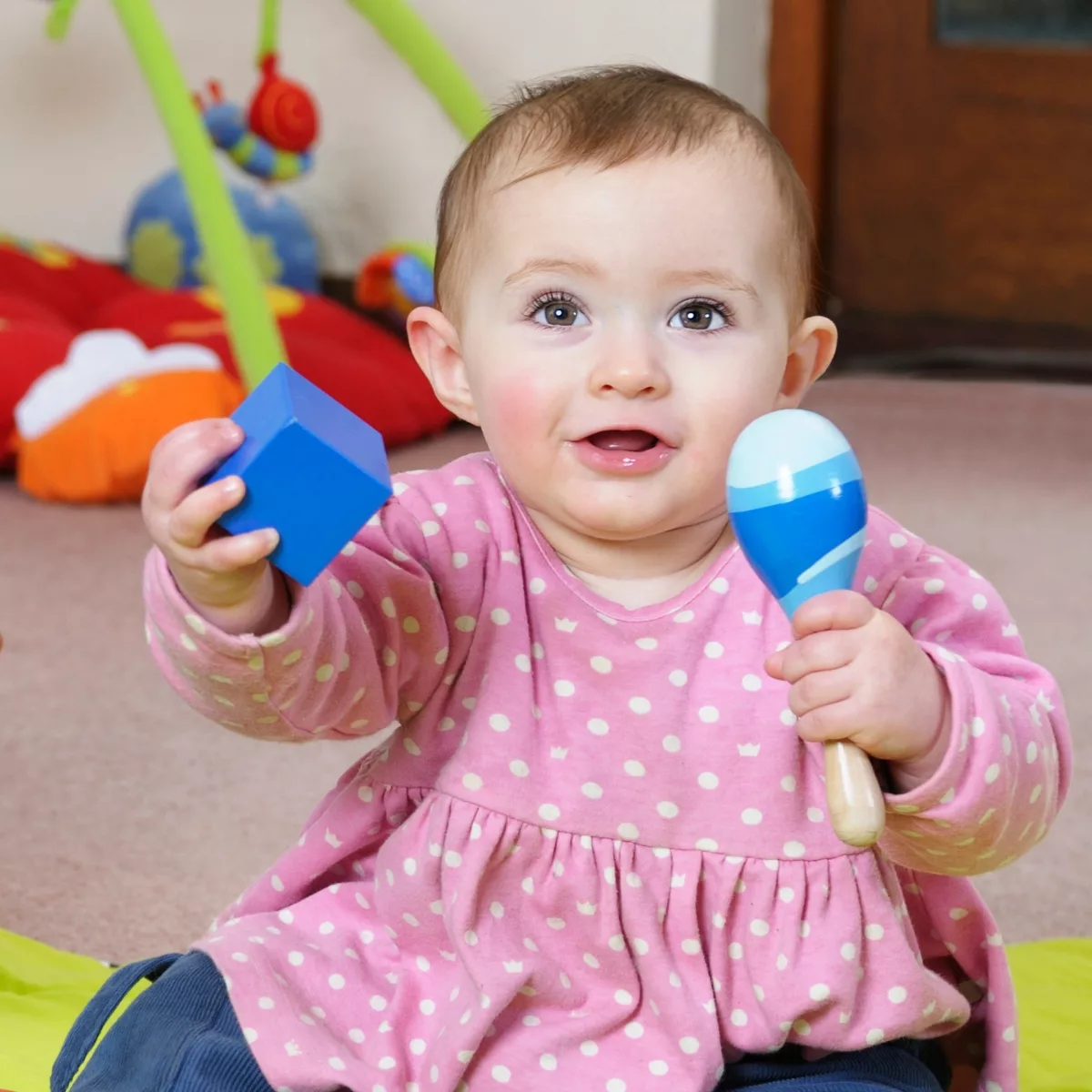 Музикални и занимателни бебешки играчки – бебе играе с дървен маракас и образователно кубче