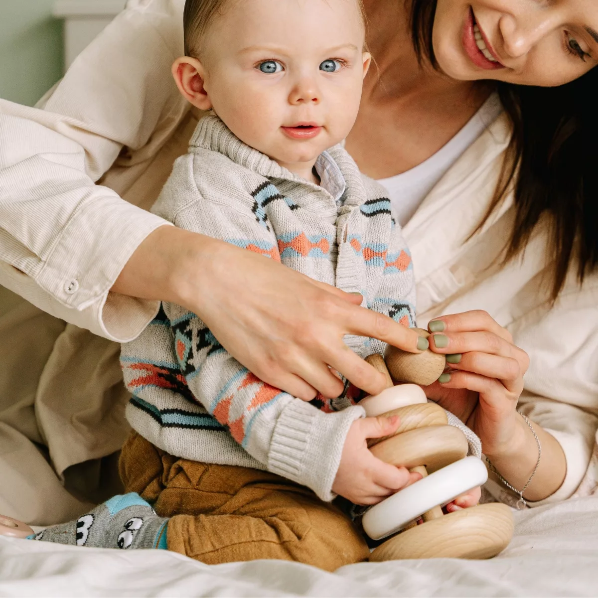 Бебе играе с дървена развиваща играчка с рингове и форми за бебета