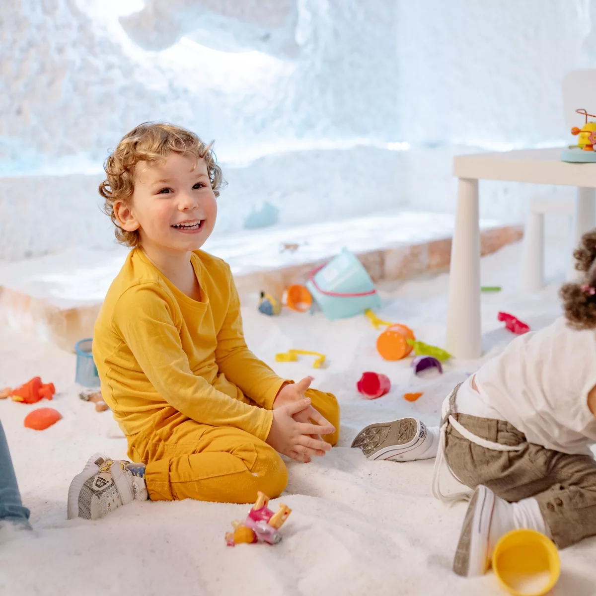 Малко дете играе със сензорни играчки в пясъчна занимателна зона