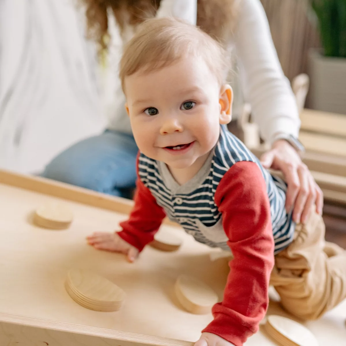 Бебе пълзи върху дървена развиваща дъска с форми и активности