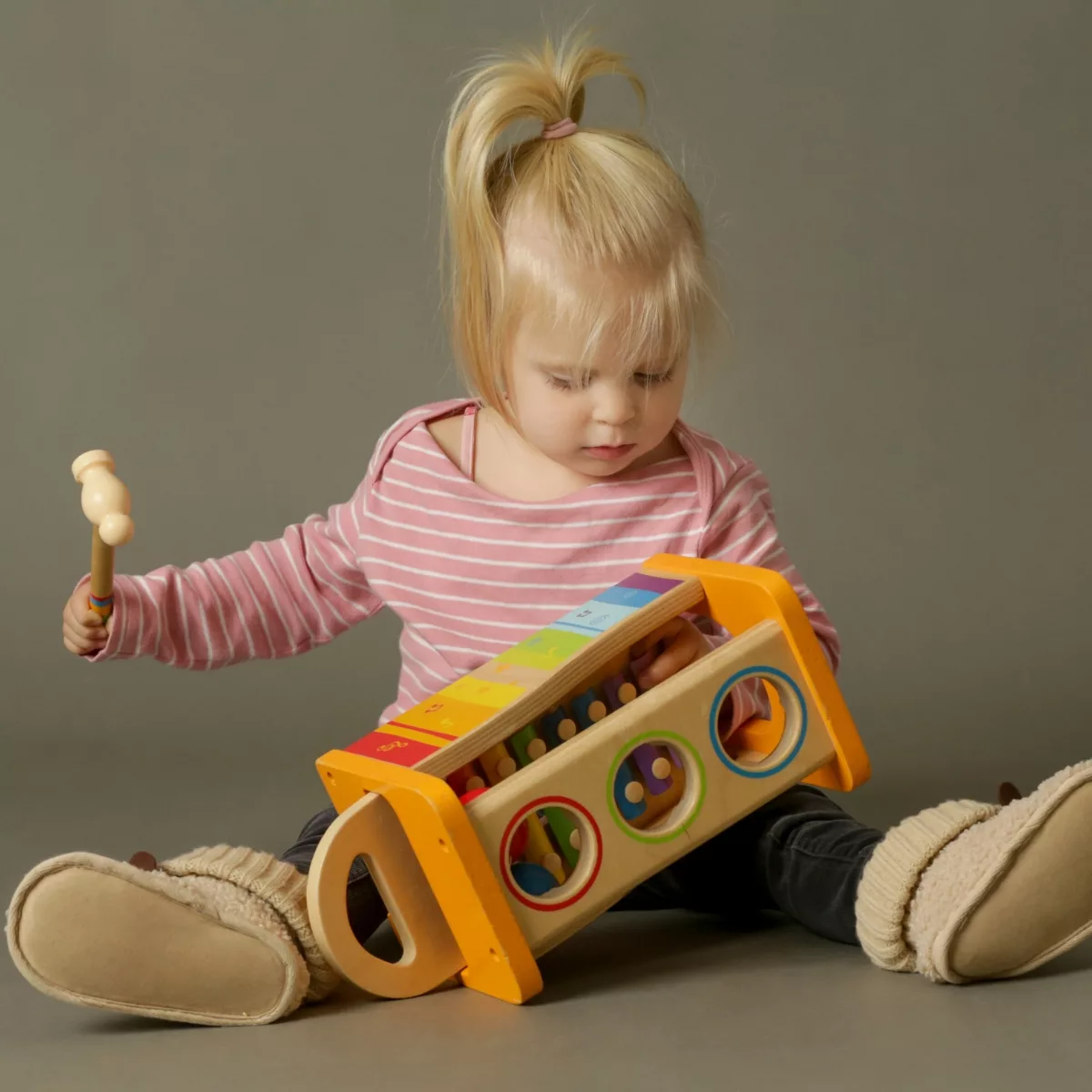 Занимателни и музикални бебешки играчки – дете играе с дървен музикален инструмент