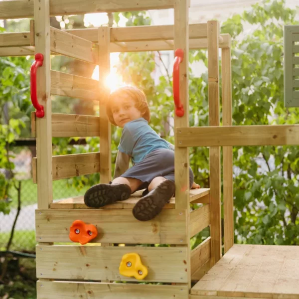 Дете играе на дървена площадка с катерушка и платформа за баланс и игра