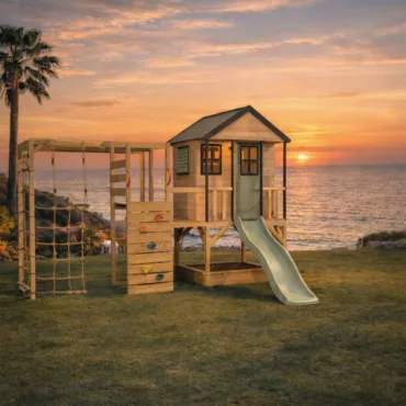 Детска дървена площадка с къщичка, пързалка и катерушка до море при залез