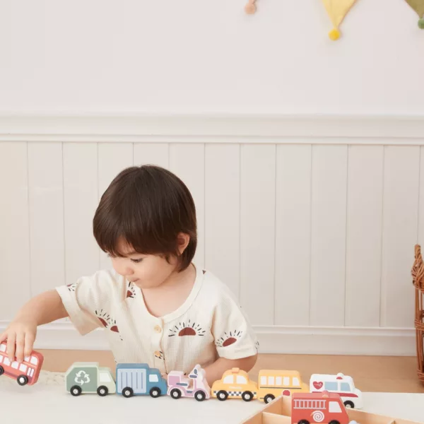 Малко дете играе с дървени превозни средства PolarB автобус линейка и такси