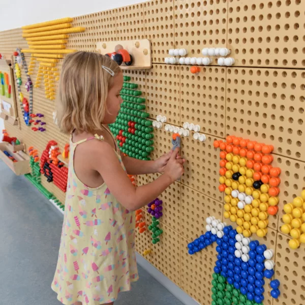 Момиче използва сив гаечен ключ Masterkidz върху STEM стена с цветни мозайки.