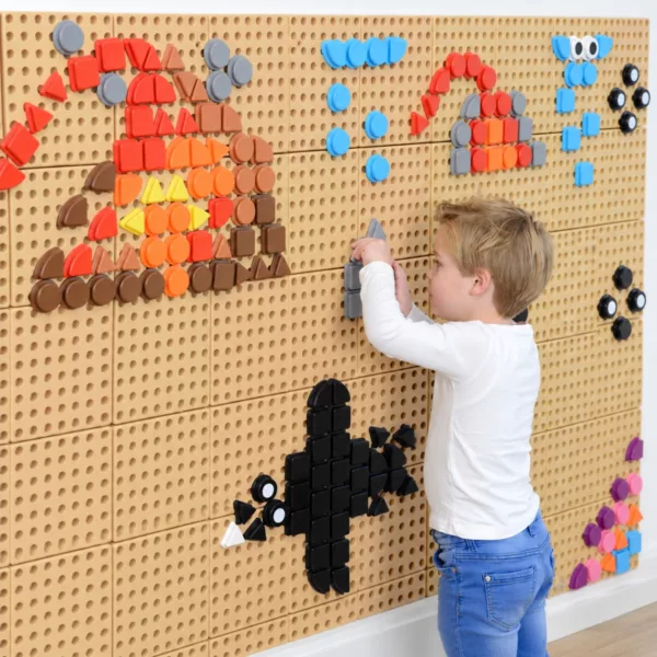 Момче подрежда цветни пластмасови елементи Masterkidz върху STEM дъска с мозайки на животни.